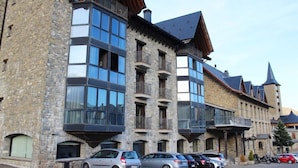 A multi-story building with stone walls and large windows, featuring balconies and a traditional architectural style. - Villa de Sallent (Sallent de Gallego)