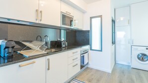 Eine moderne Küche mit weißen Schränken, einer Mikrowelle, einer Kaffeemaschine und einer Waschmaschine.