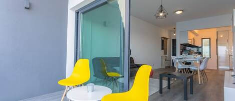 A modern dining area with a glass partition, a round table, and yellow chairs.