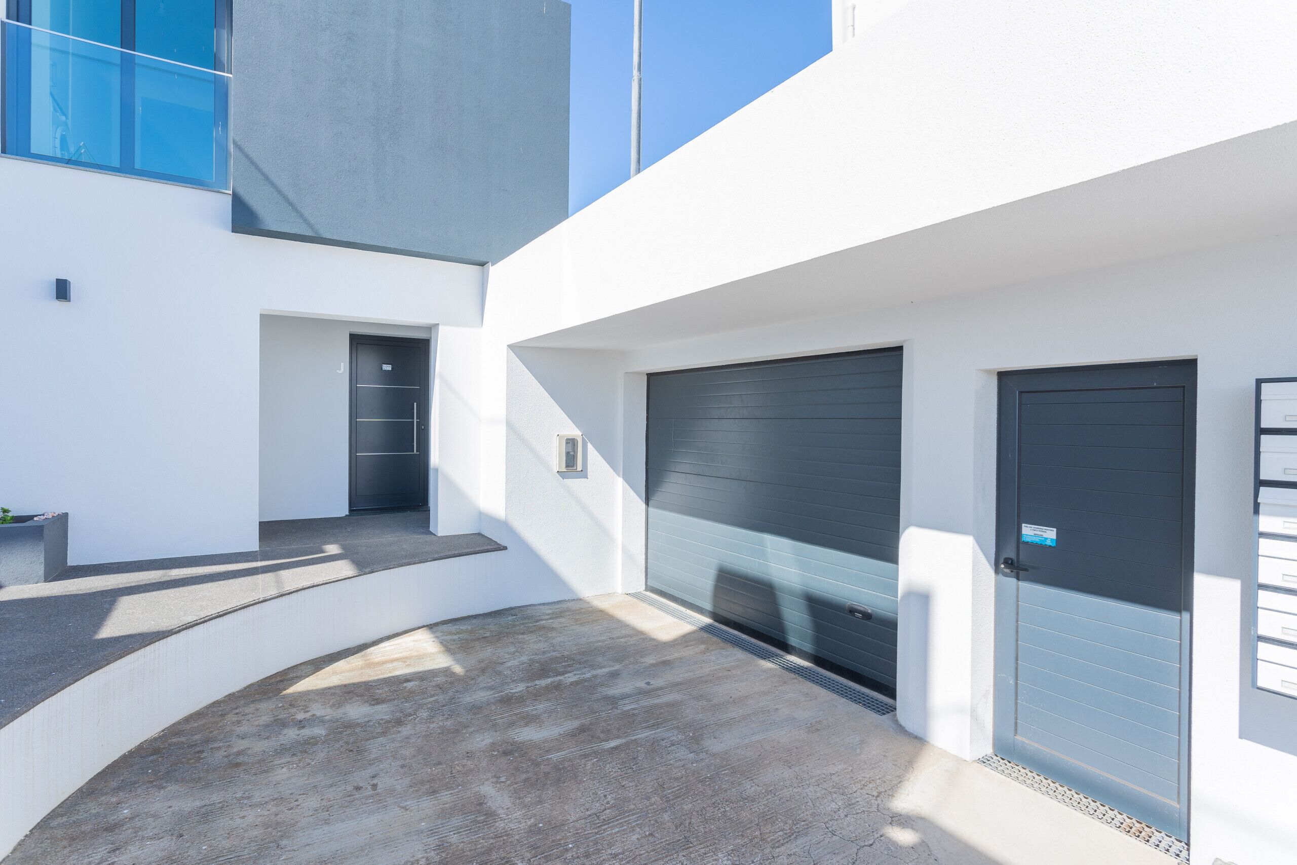 A modern building with a concrete floor, a garage door, and a door with a sign.