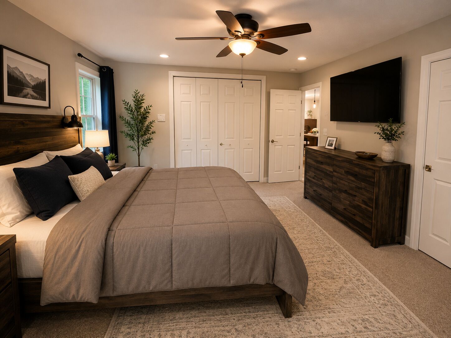 A bedroom with a bed, a ceiling fan, a dresser, a TV, and a door.