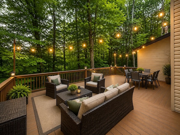 Eine Terrasse mit Korbmöbeln, Lichterketten und Blick auf einen Wald.