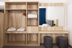 A modern room with a wooden wardrobe, a mirror, a desk, and two ottomans. - Baia Dei Mulini (Erice)