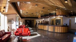 A spacious lobby with a reception desk, red leather sofas, and a polished floor.