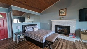 Ein Schlafzimmer mit Bett, Nachttisch, Lampe und Kamin.