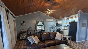 Ein Wohnzimmer mit braunem Ledersofa, einem Holztisch und einem Deckenventilator.