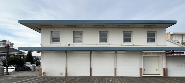 A two-story building with a flat roof, multiple windows, and a closed garage door.