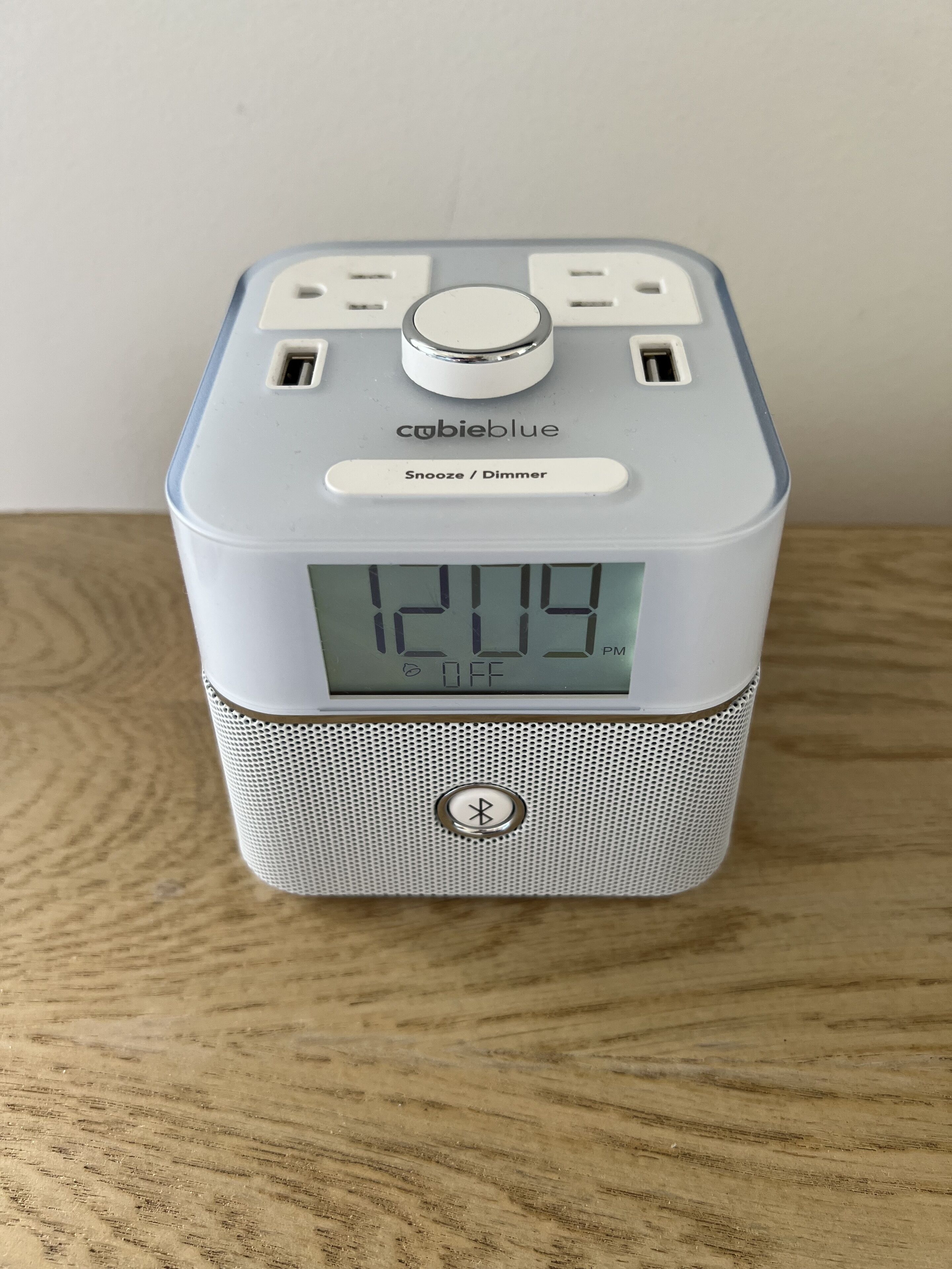 A portable speaker with a digital display, a power button, and a speaker grille.