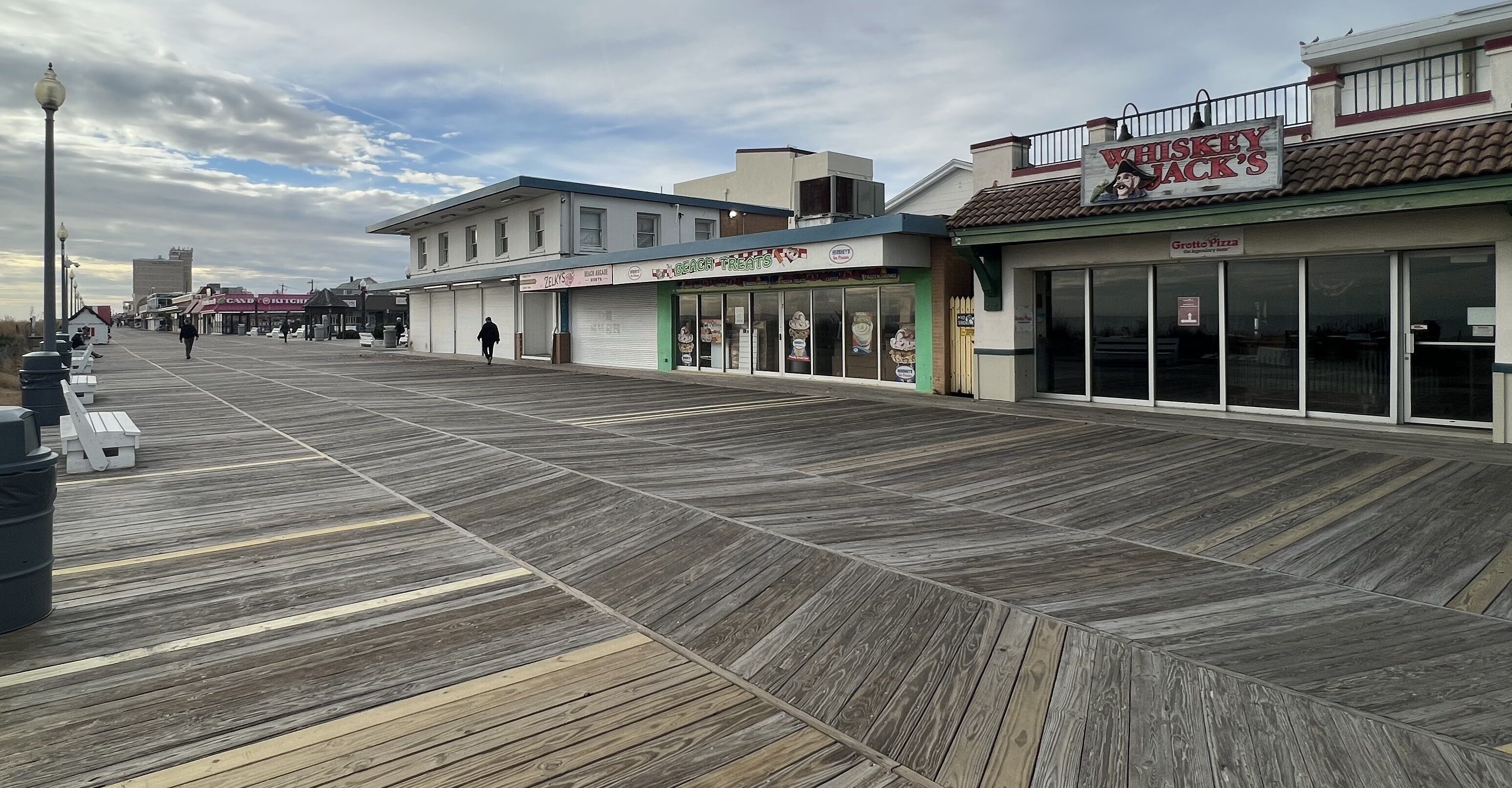 A boardwalk with shops, including a bakery and a pizza place.
