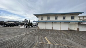 A waterfront property with a large wooden deck, a building with multiple garage doors, and a gazebo in the background.