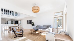 A spacious living area with a high ceiling, a dining table, a sofa, and a coffee table. - STUNNING! Ocean Views!! Lux Remodeled Modern Beach House. +PELETON . (Oxnard)