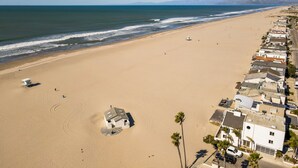 A coastal beach with a row of houses along the shore, a lifeguard tower, and a clear view of the ocean. - STUNNING! Ocean Views!! Lux Remodeled Modern Beach House. +PELETON . (Oxnard)