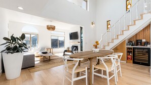A spacious living area with a wooden dining table, white chairs, and a large potted plant. - STUNNING! Ocean Views!! Lux Remodeled Modern Beach House. +PELETON . (Oxnard)