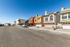 Una calle residencial con casas, cielo despejado y coches estacionados.