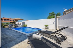 A rooftop pool with a clear blue pool, two lounge chairs, and a small potted plant. - Apartment Vedran with heated pool, in Porec (Kukci)