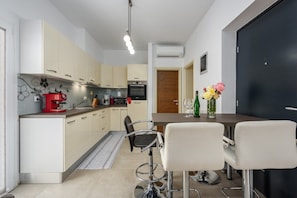 A modern kitchen with a dining area, featuring a coffee machine, a TV, and a vase with flowers. - Apartment Vedran with heated pool, in Porec (Kukci)