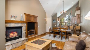A cozy living room with a stone fireplace, a wooden coffee table, and a leather sofa.