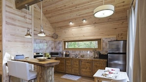 L’intérieur d’un chalet en bois rustique comprend une cuisine, un coin repas et un bar.