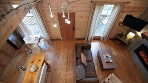 L'intérieur d'un chalet en bois, avec un canapé, une table et un téléviseur.