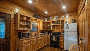 A wooden kitchen with built-in cabinets, a microwave, stove, and refrigerator.