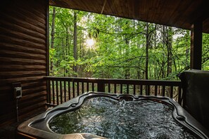 Ein Whirlpool mit Holzterrasse und Blick auf einen Wald.