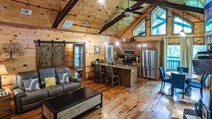 Un intérieur de cabine spacieux, avec un plafond en bois, un coin repas, une cuisine et un salon comprenant un canapé et une table basse.