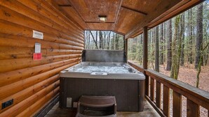 Ein Whirlpool in einer Blockhütte mit Blick auf einen Wald.