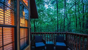 Una terrazza in legno con mobili in vimini e vista su una foresta.