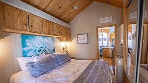 Una camera da letto con un letto grande, soffitto in legno e un dipinto di un fiore.
