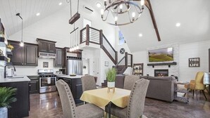 Amplia sala de estar con mesa de comedor, asientos cómodos, chimenea y televisión.