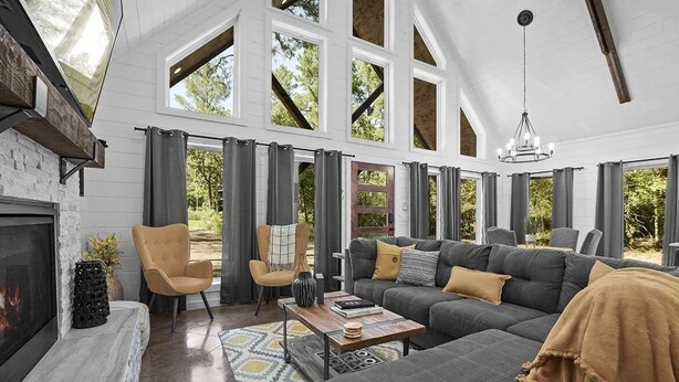 Un salón amplio con chimenea, ventanas grandes y un techo alto.