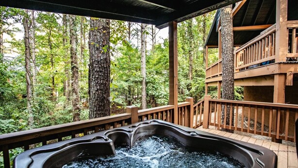 A hot tub on a wooden deck with a forest view. - Hillside Delight-1 BR-Timber Creek Trails (Broken Bow)