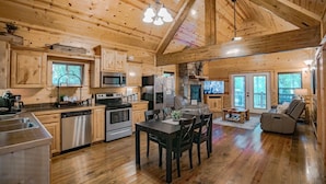 A wooden cabin interior with a kitchen, dining area, and a cozy seating area. - Hillside Delight-1 BR-Timber Creek Trails (Broken Bow)