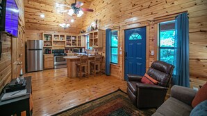Interior de una cabaña de madera con cocina, comedor y sala de estar.