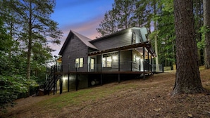A rustic cabin with a wooden exterior, a covered deck, and a staircase leading to the main entrance.