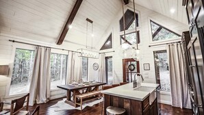 Een ruime keuken met een groot kookeiland, houten vloeren en een hoog plafond met zichtbare balken.