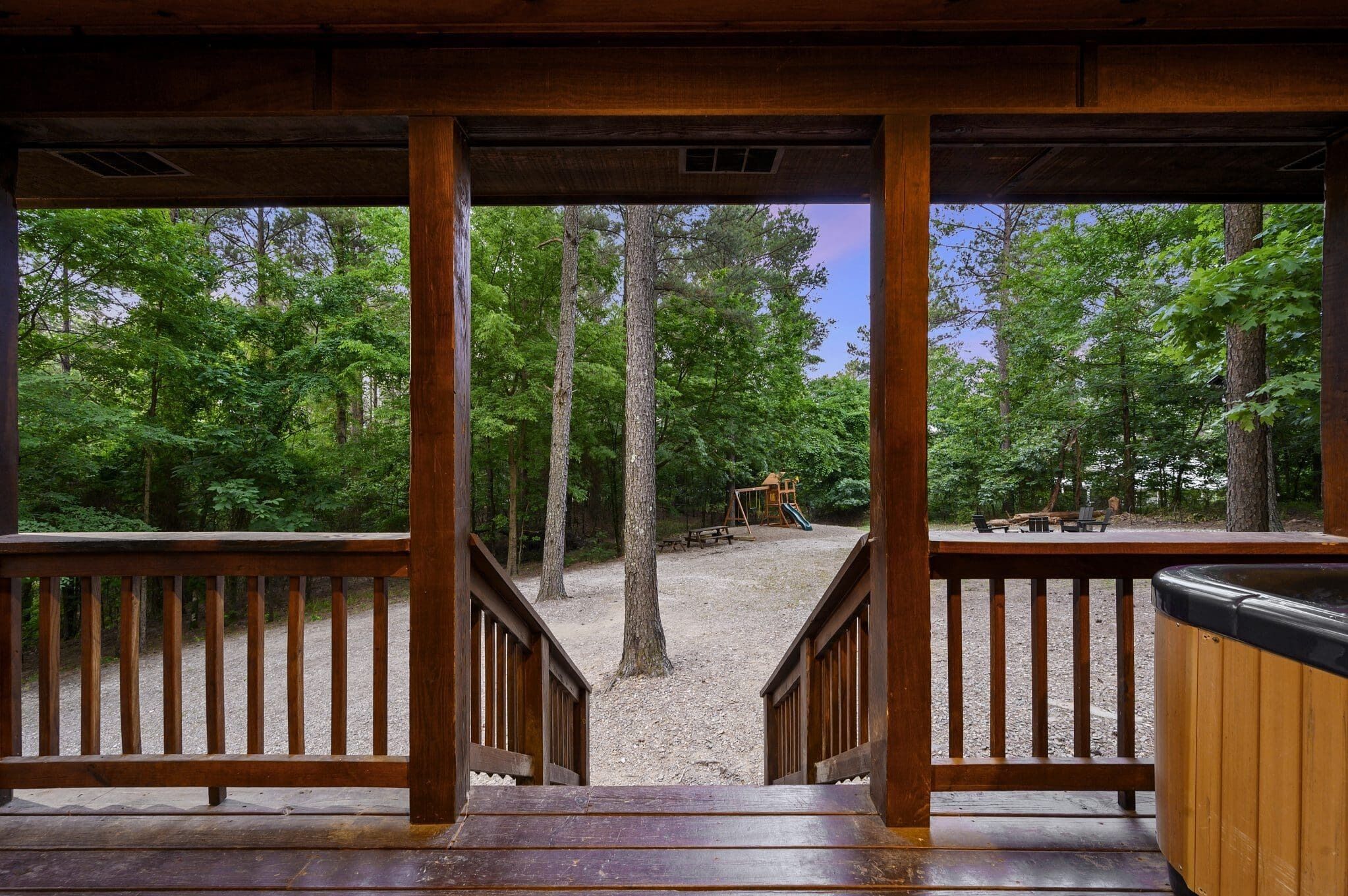 A wooden deck with a view of a playground and trees.