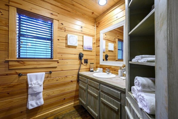 Un baño con paneles de madera, un lavamanos, un espejo y un perchero para toallas.