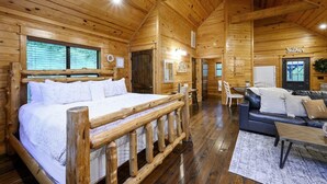 A log cabin interior with a large bed, a sofa, and a dining area. - Summer Brook Studio-Creekside-Timber Creek Trails (Broken Bow)