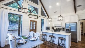 Una cocina amplia con una isla central, taburetes de bar y un refrigerador grande.