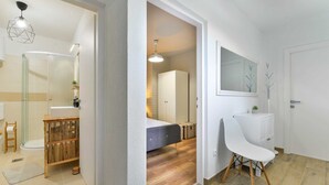 Un baño moderno con cabina de ducha de vidrio, tocador de madera y una silla blanca.