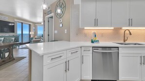 Une cuisine moderne avec des meubles blancs, un lave-vaisselle encastré et des luminaires suspendus.