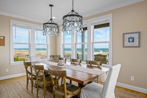 A dining area with a large table, chairs, and two chandeliers.