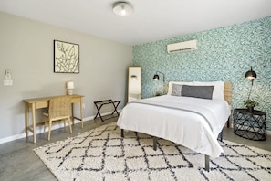 A bedroom with a bed, a desk, a chair, a mirror, and a round side table. - The Greenhouse: Modern Rural Escape with Fire Pit (Ithaca)