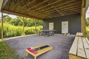 Un espace extérieur abrité, équipé d’une table et de chaises, d’un banc et d’une terrasse en bois.