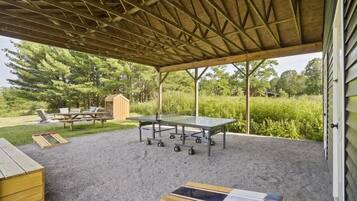 Une terrasse extérieure couverte équipée d’une table de ping-pong, d’une table de pique-nique et de chaises longues.