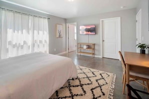 A bedroom with a bed, a TV, a desk, and a chair. - The Greenhouse: Modern Rural Escape with Fire Pit (Ithaca)