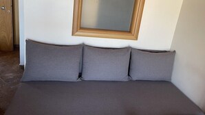 A room with a bed, a wooden door, and a mirror on the wall. - Aria Hotel (Skiathos)
