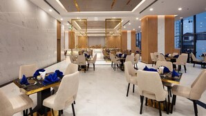 A modern dining area with marble walls, gold accents, and a view of the cityscape. - Virgo Hotel (Nha Trang)