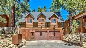 A two-story wooden cabin with a garage, surrounded by trees and a stone wall. - Mv30 unique Lake Tahoe cabin with great wifi (South Lake Tahoe)